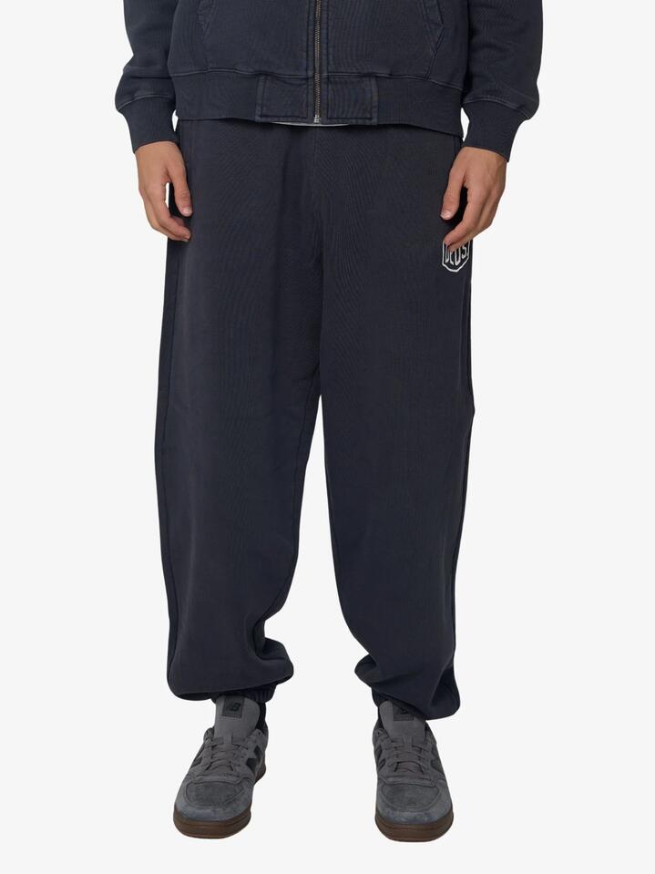 Image of a model wearing Pants. Productname: Deus Shield Garment Dyed Track Pants in Black colour by brand - Deus