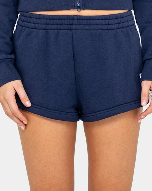 Image of a model wearing Outerwear. Productname: rusty Womens Retro Lines Mini Fleece Elastic Waist Shorts Navy Blue - in Navy Blue colour by brand - Rusty