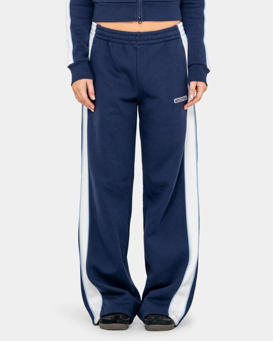 Image of a model wearing Pants. Productname: rusty Womens Retro Lines Wide Leg Track Pants Navy Blue - in Navy Blue colour by brand - Rusty