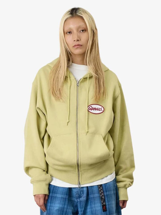 Image of a model wearing Outerwear. Productname: Gramicci Oval Patch Zip Hooded Sweatshirt in Lime colour by brand - Gramicci