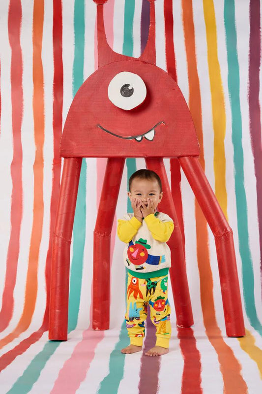 Image of a model wearing Pants. Product name - Monster Play Baby Track Pant in Yellow colour by brand - Gorman