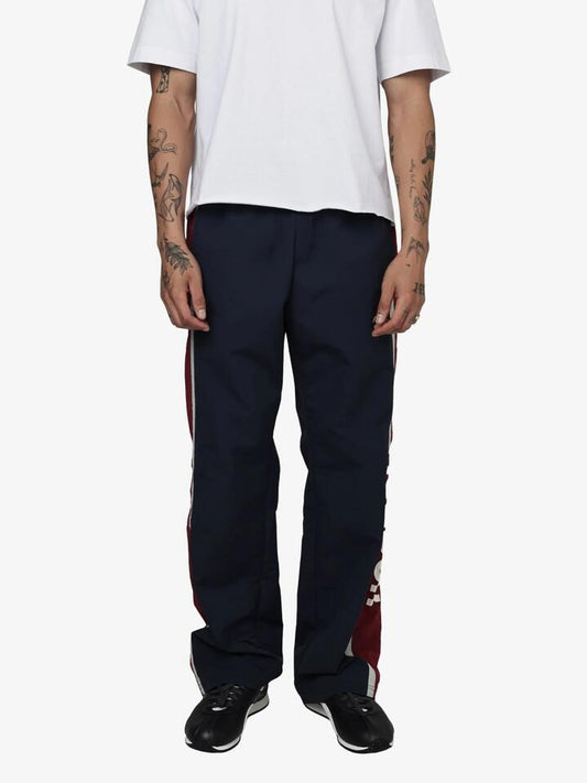 Image of a model wearing Pants. Productname: Reebok Vector Woven Wide Leg Trackpants in Dark Indigo/Heritage Red colour by brand - Reebok