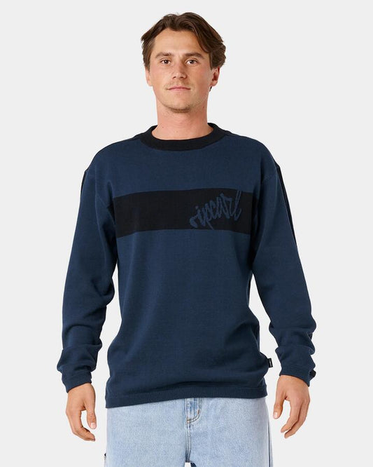Image of a model wearing Tops. Product name - Rip Curl Mens Panel Beater Knit Crew Neck Dark Navy in Dark Navy colour by brand - Rip Curl