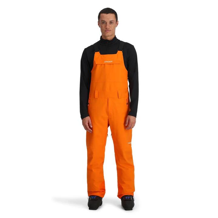 Image of a model wearing Pants. Product name - Spyder Mens Terrain Bib Snow Pants Orange Shock in Orange Shock colour by brand - Spyder