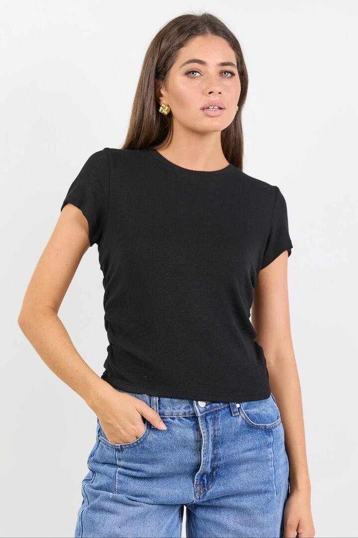 Image of a model wearing Tops. Product name - Onboard Black Rib Rouched Side Crop Tee in Black colour by brand - Among the Brave