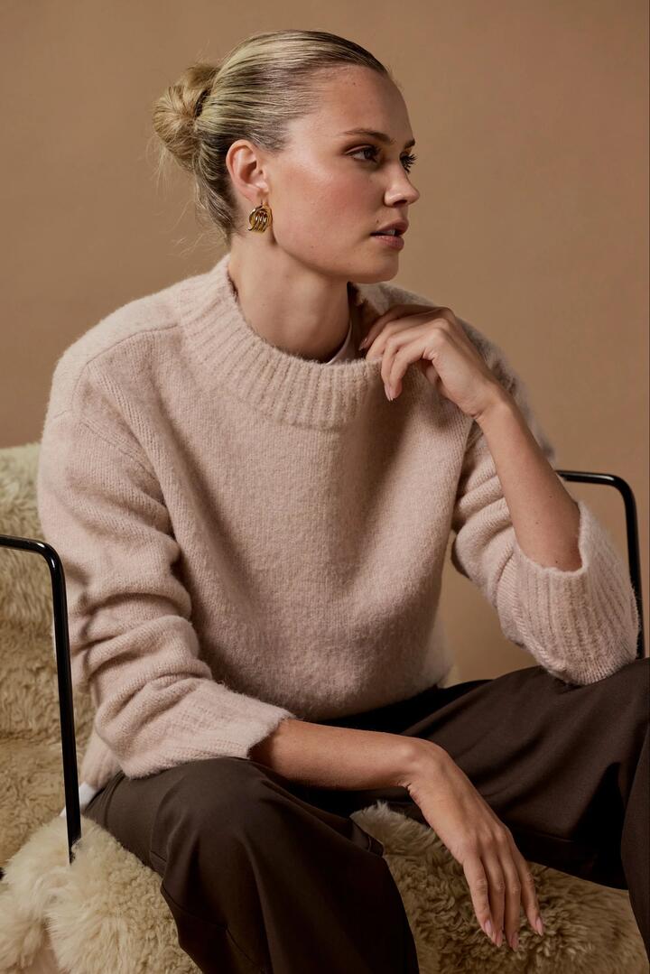 Image of a model wearing Outerwear. Product name - Cocoon Stone Relaxed Knit Mock Neck Jumper in Stone colour by brand - Among the Brave