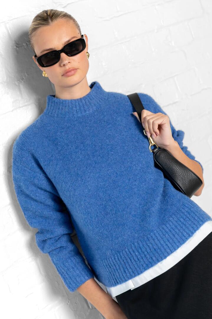 Image of a model wearing Outerwear. Product name - Cocoon Azure Relaxed Knit Mock Neck Jumper in Azure colour by brand - Among the Brave