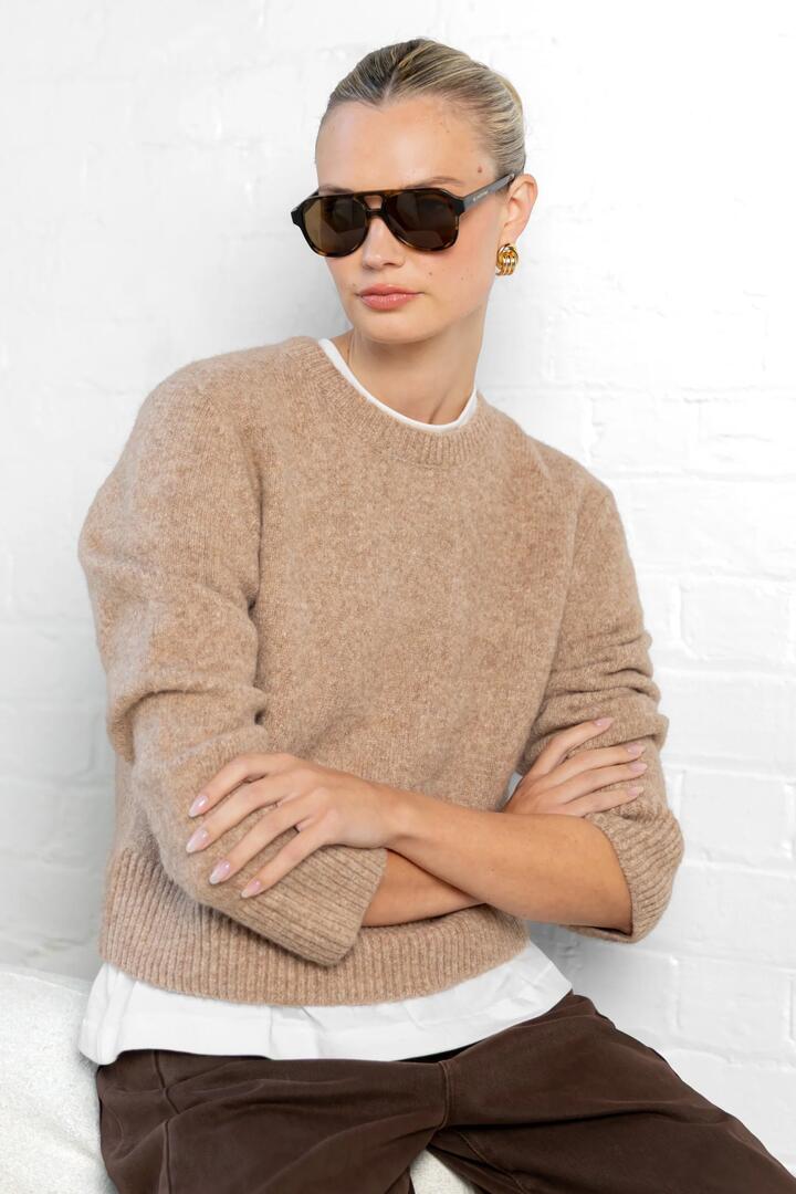 Image of a model wearing Outerwear. Product name - Enhance Biscuit LS Soft Knit Crewneck Jumper in Biscuit colour by brand - By Rosa.