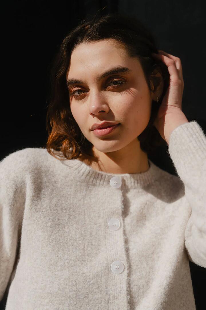 Image of a model wearing Outerwear. Product name - Crest Oat Marle Crewneck Cardigan in Oat Marle colour by brand - Stories be Told