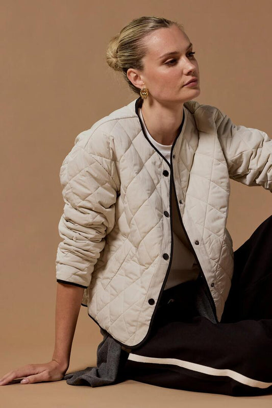 Image of Coats & Jackets. Product name - Apex Bone Collarless Quilted Contrast Piping Puffer Jacket in Bone colour by brand - Stories be Told