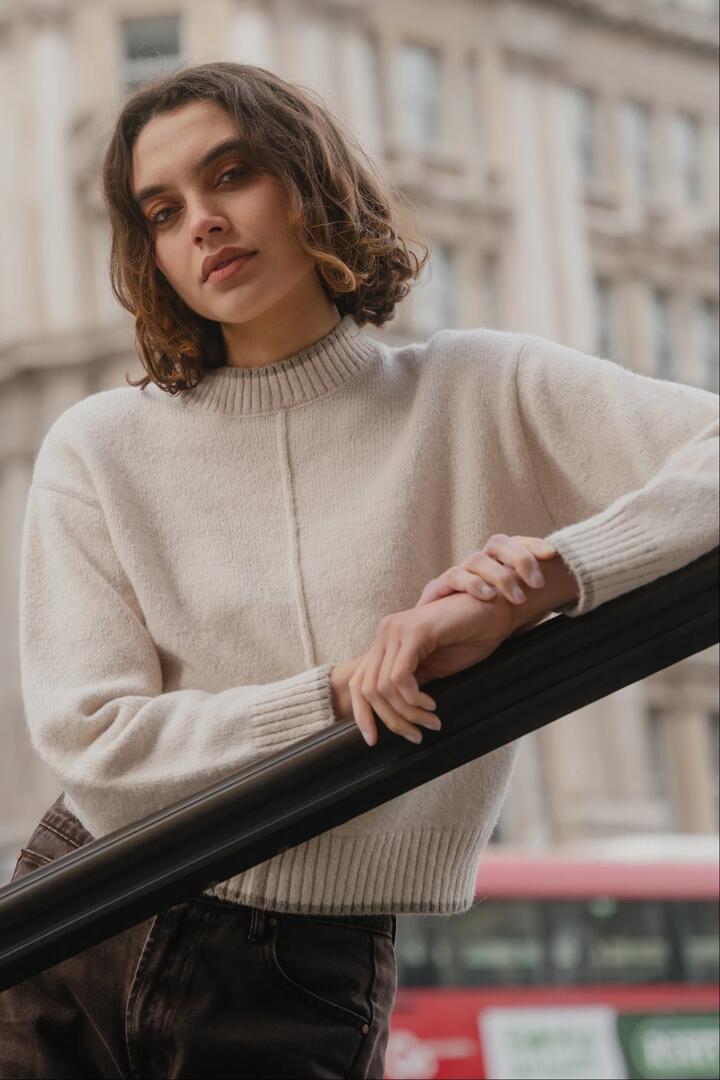 Image of a model wearing Outerwear. Product name - Edge Ivory Mock Neck Contrast Trim Jumper in Ivory colour by brand - Among the Brave