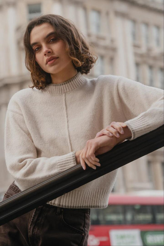 Image of a model wearing Outerwear. Product name - Edge Ivory Mock Neck Contrast Trim Jumper in Ivory colour by brand - Among the Brave