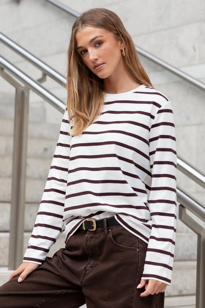 Image of a model wearing Tops. Product name - Tether Chocolate White Stripe LS Boxy Tee in Chocolate White Stripe colour by brand - RE:UNION Label