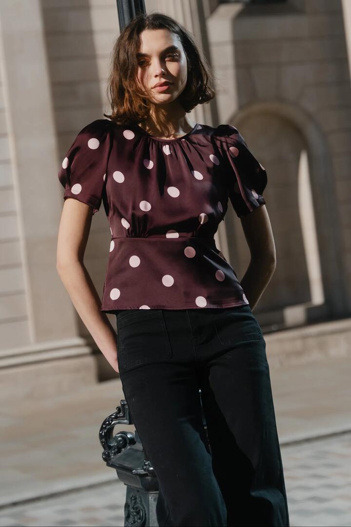 Image of a model wearing Tops. Product name - Uplifting Plum Polka Dot Satin Short Sleeve Top in Plum Polka Dot colour by brand - Stories be Told