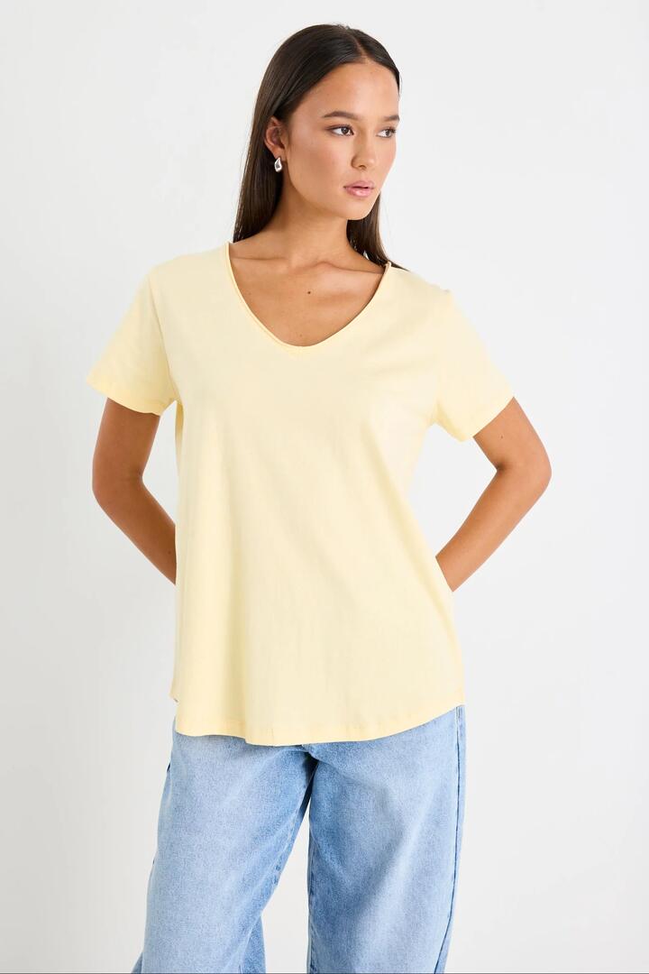 Image of a model wearing Tops. Product name - Poetry Butter V Neck Short Sleeved Tee in Butter colour by brand - Ivy + Jack