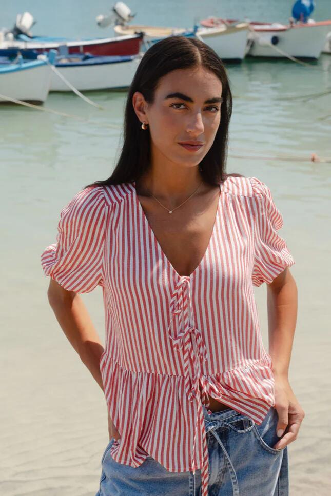 Image of a model wearing Tops. Product name - Restore Red Stripe Tie Front Peplum SS Top in Red Stripe colour by brand - Stories be Told