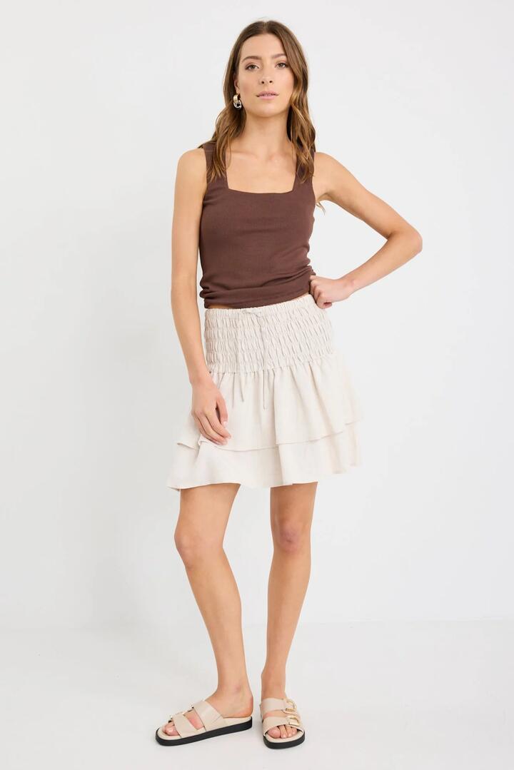 Image of a model wearing Skirts. Product name - Lennox Natural Shirred Linen Blend Tiered Mini Skirt in Natural colour by brand - Ivy + Jack