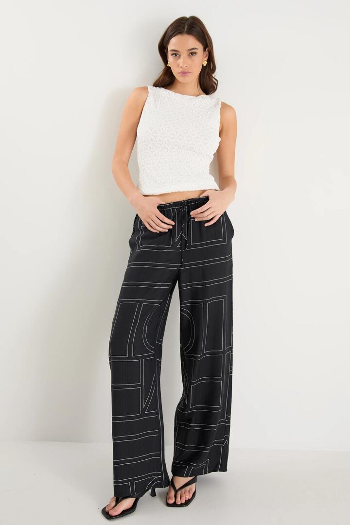 Image of a model wearing Pants. Product name - Clever Black Lines Drawcord Wide Leg Pants in Black Ivory Lines colour by brand - Among the Brave