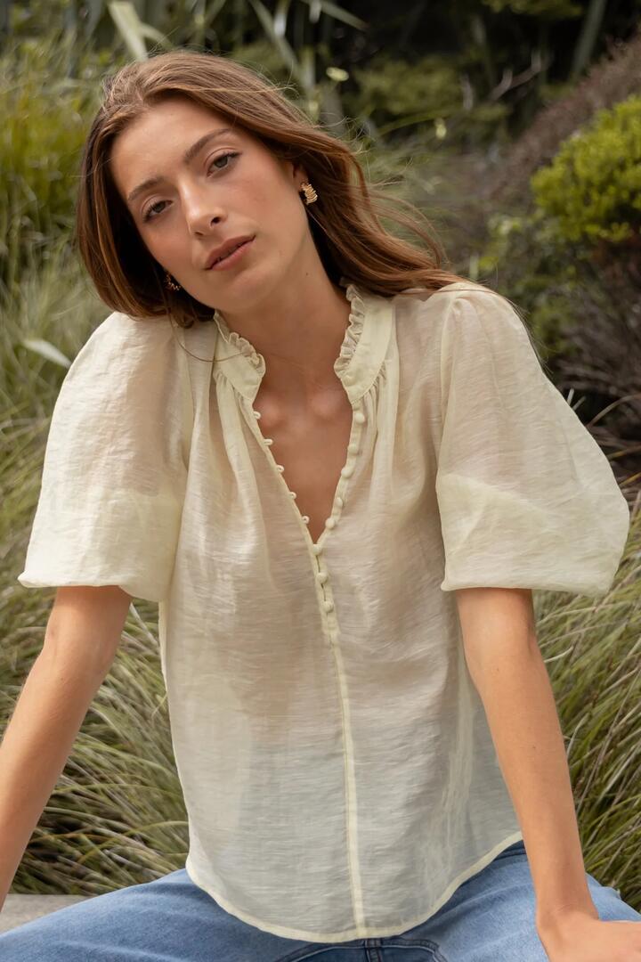 Image of a model wearing Tops. Product name - Closure Sunshine Sheer High Neck Buttoned SS Top in Sunshine colour by brand - Ivy + Jack