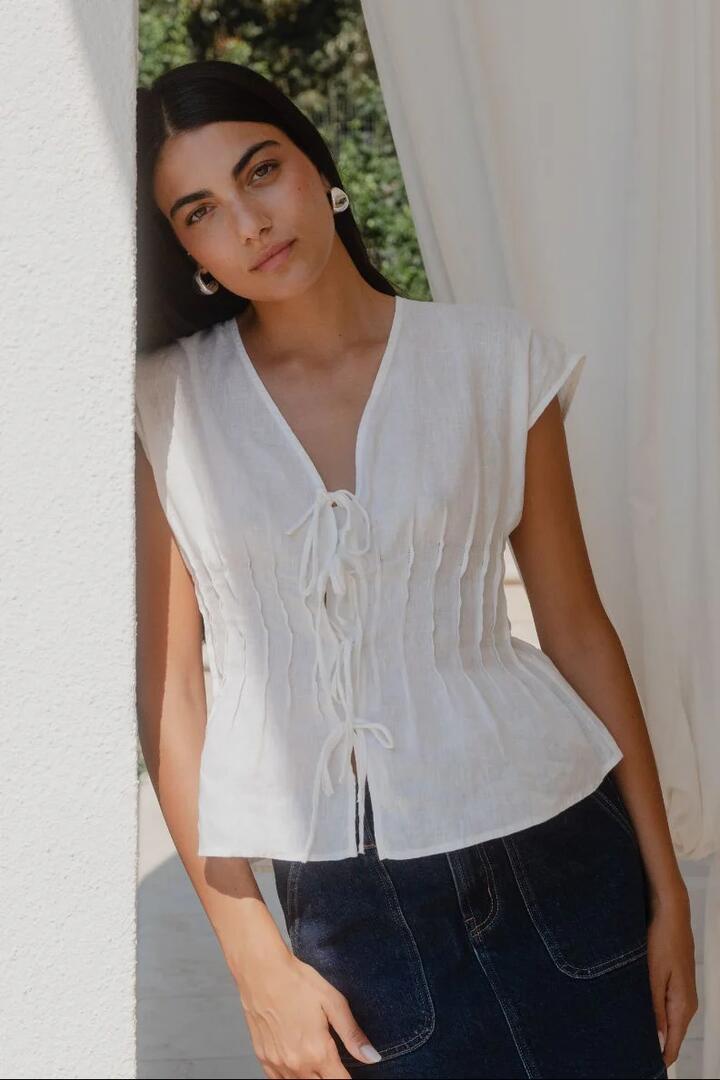 Image of a model wearing Tops. Product name - Nouveau Ivory Linen Tie Front Vest in Ivory Linen colour by brand - Ivy + Jack
