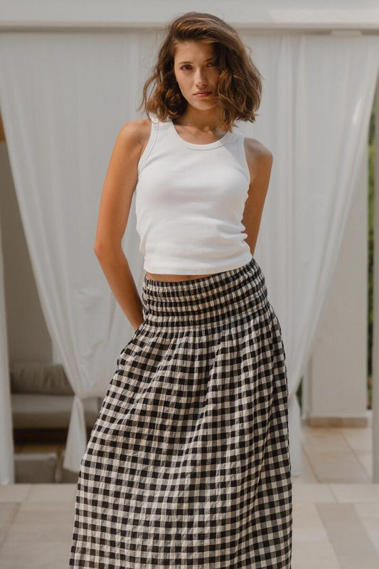 Image of a model wearing Skirts. Product name - Cheerful Black Gingham Cotton Shirred Waist Maxi Skirt in Black Gingham colour by brand - Ivy + Jack