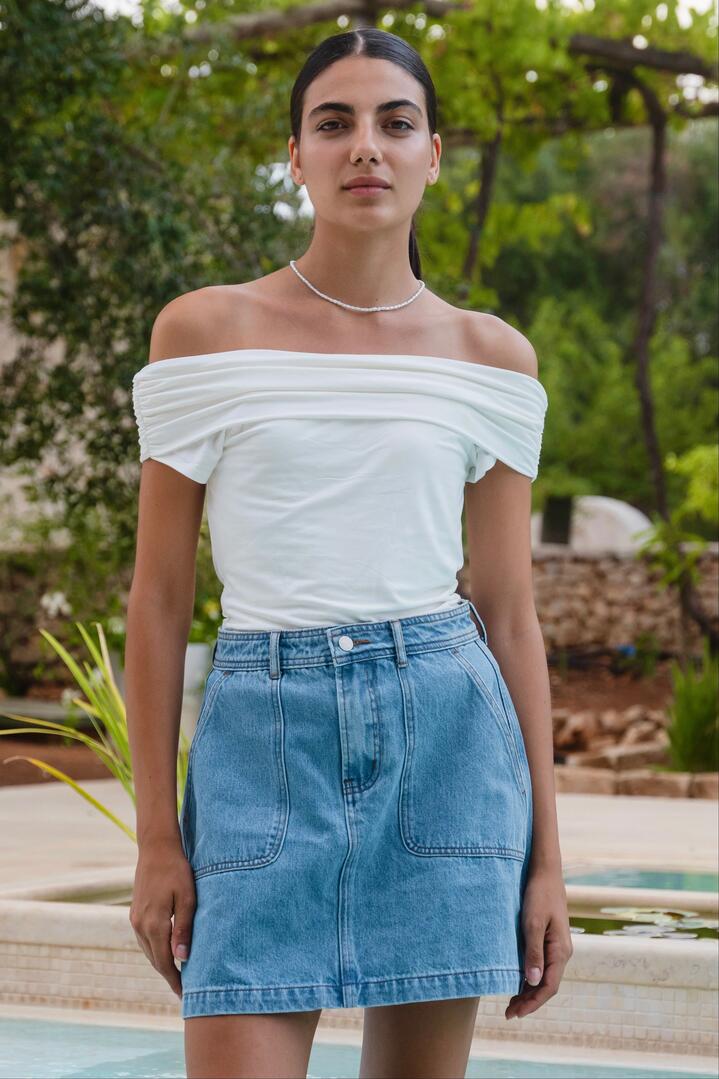 Image of a model wearing Skirts. Product name - Orchard Mid Blue Pocket Front Denim Mini Skirt in Mid Blue colour by brand - Ivy + Jack