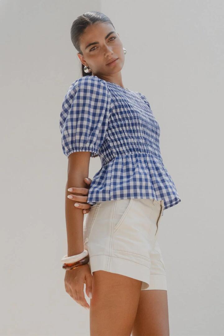 Image of a model wearing Tops. Product name - Requite Blue Gingham Shirred Body SS Top in Navy Gingham colour by brand - Among the Brave