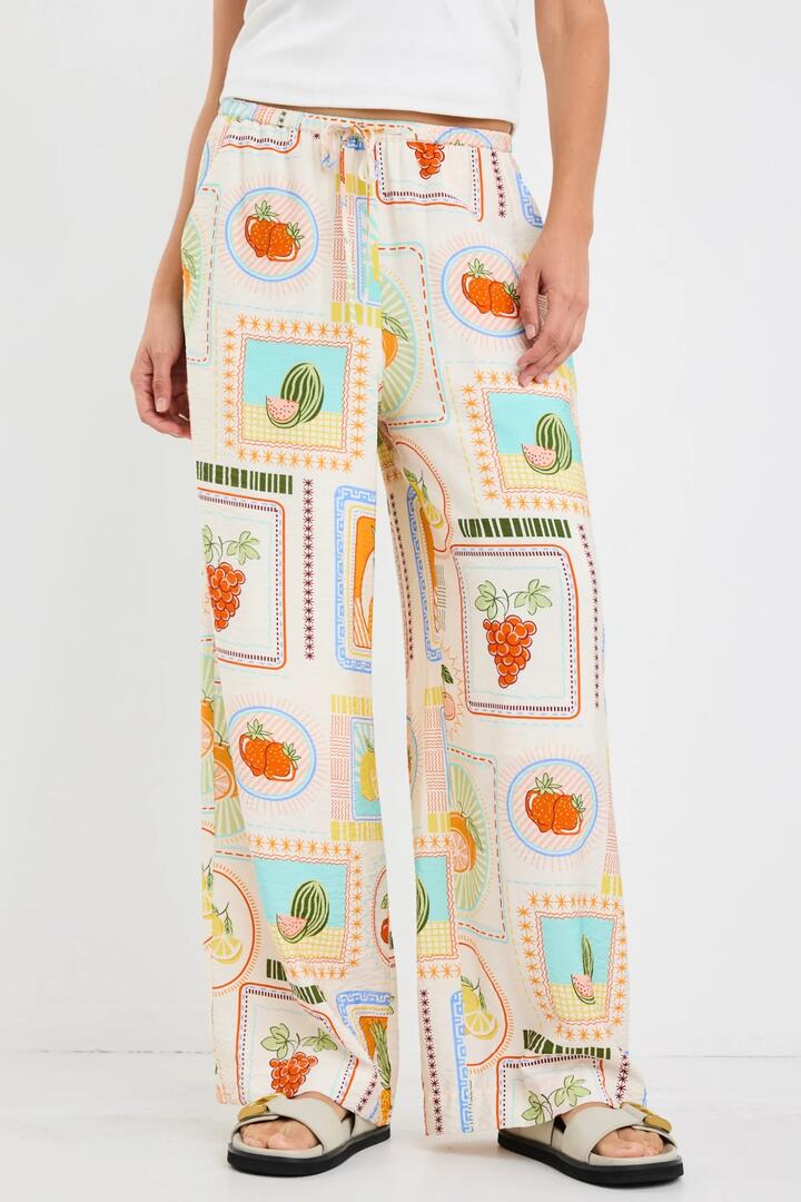 Image of a model wearing Pants. Product name - Travel Cream Tropical Postcard Wide Leg Pull On Pants in Tropical Postcard colour by brand - By Rosa.