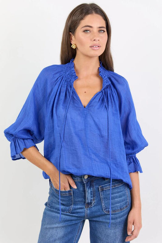 Image of a model wearing Tops. Product name - Expedition Blue Shirred Neck Short Sleeve Top in Blue colour by brand - Among the Brave