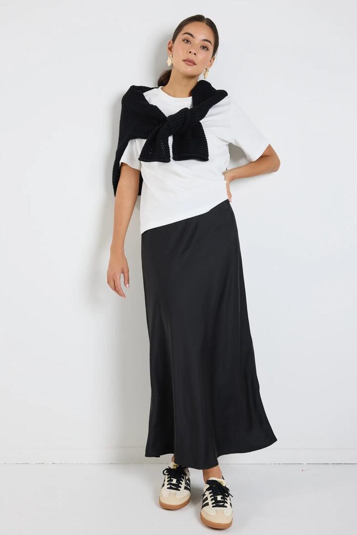 Image of a model wearing Skirts. Product name - Rosette Black Satin Bias Midi Skirt in Black colour by brand - Ivy + Jack
