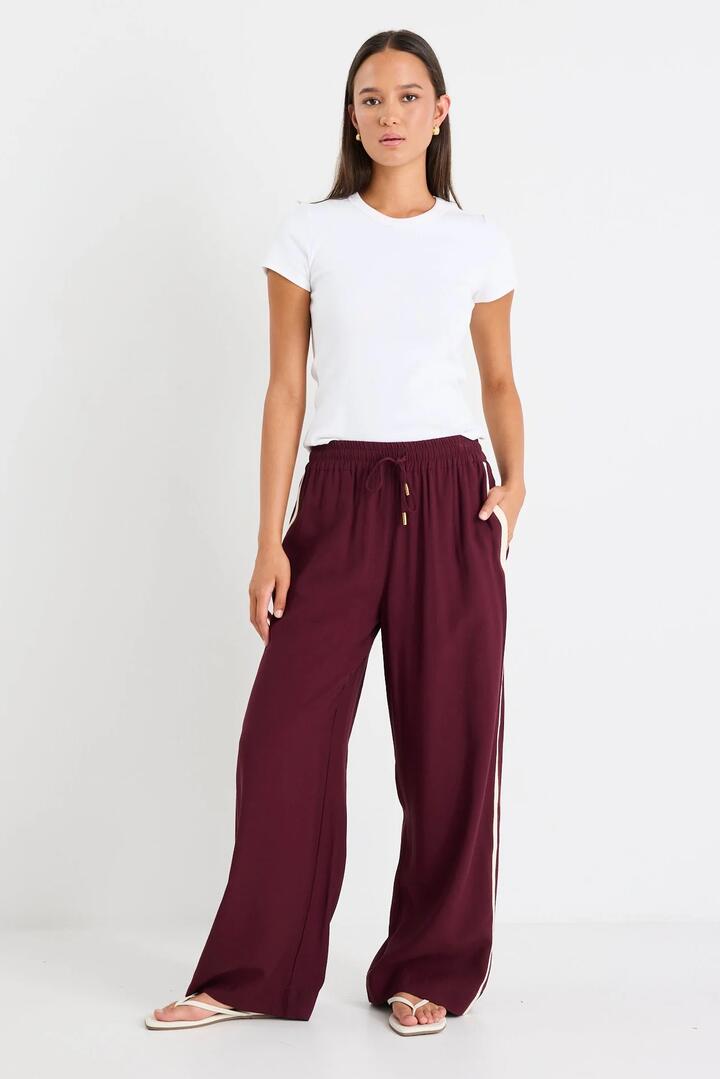 Image of a model wearing Pants. Product name - Townie Burgundy Plum Side Stripe Elastic Waist Pants in Burgundy Plum colour by brand - Stories be Told