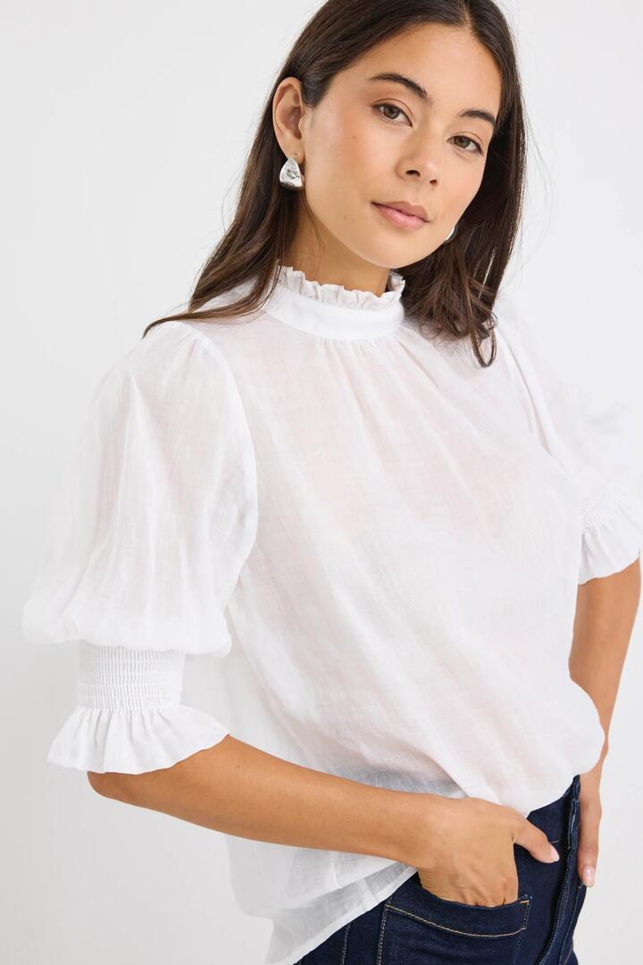 Image of a model wearing Tops. Product name - Verse Ivory Sheer High Neck Short Sleeve Top in Ivory colour by brand - By Rosa.