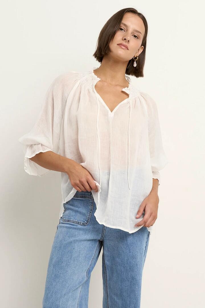 Image of a model wearing Tops. Product name - Expedition Ivory Ramie Shirred Neck Short Sleeve Top in Ivory Ramie colour by brand - Among the Brave