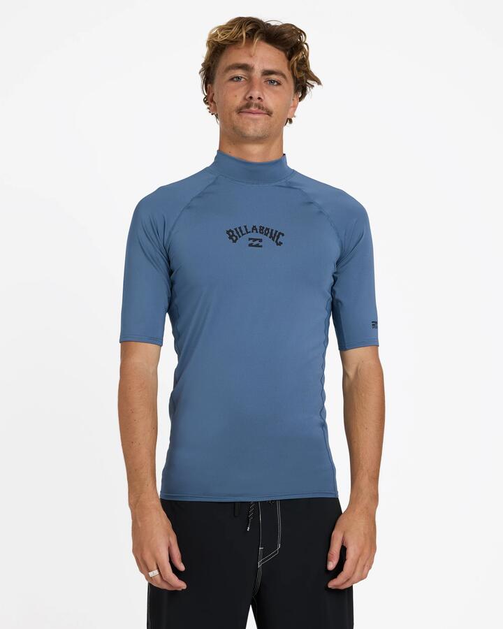 Image of a model wearing Tops. Product name - Billabong Mens All Day Arch Pf Short Sleeve Rash Vest Steel Blue in Steel Blue colour by brand - Billabong