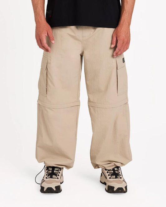 Image of a model wearing Pants. Product name - Billabong Mens Strike Mission Zip Off Cargo Pants Bone in Bone colour by brand - Billabong