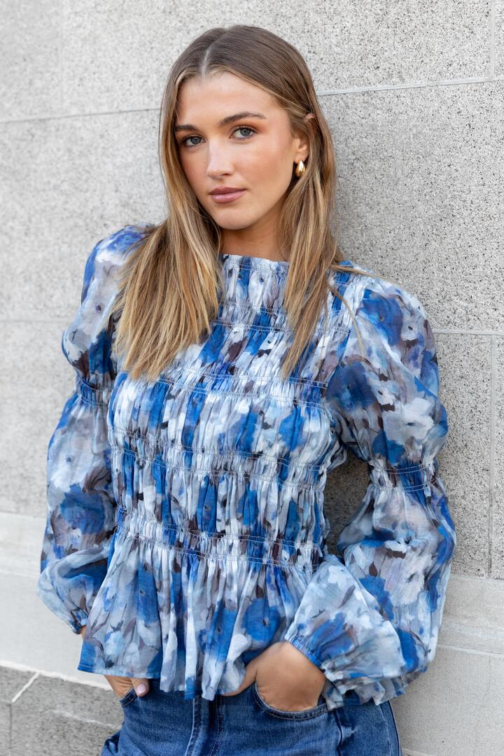 Image of a model wearing Tops. Product name - Required Sky Blue Floral LS Shirred Bodice Top in Sky Blue Floral colour by brand - Among the Brave