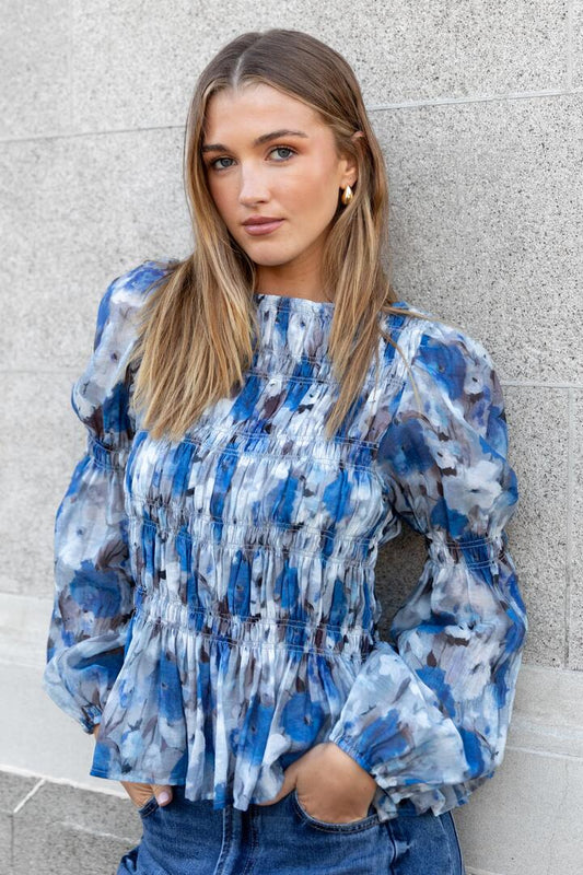 Image of a model wearing Tops. Product name - Required Sky Blue Floral LS Shirred Bodice Top in Sky Blue Floral colour by brand - Among the Brave