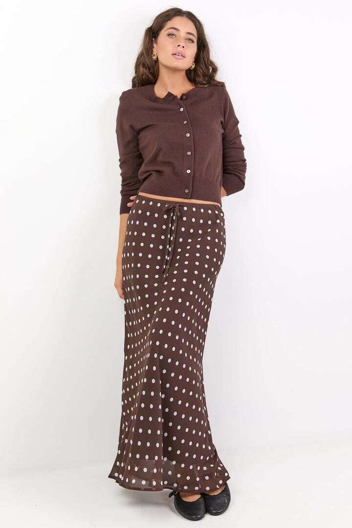 Image of a model wearing Skirts. Product name - Rally Chocolate Polka Dot Georgette Tie Waist Bias Maxi Skirt in Chocolate Polka Dot colour by brand - Among the Brave