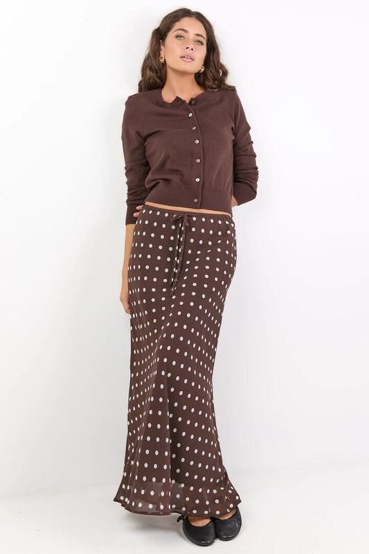 Image of a model wearing Skirts. Product name - Rally Chocolate Polka Dot Georgette Tie Waist Bias Maxi Skirt in Chocolate Polka Dot colour by brand - Among the Brave