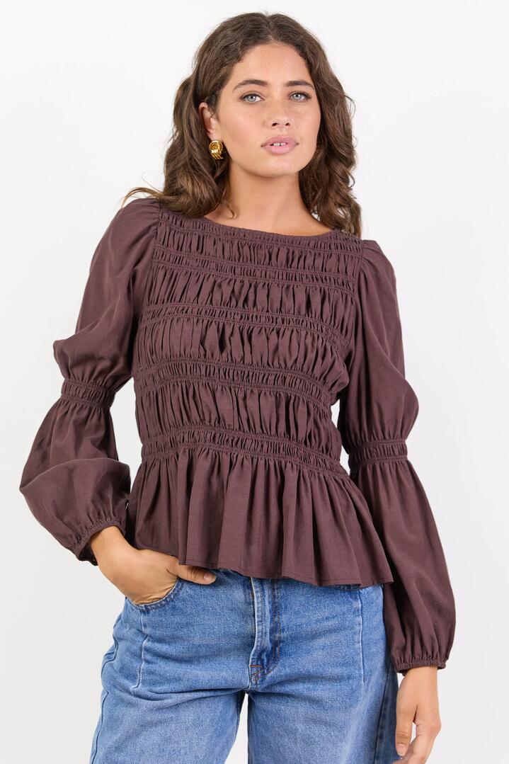 Image of a model wearing Tops. Product name - Required Chocolate LS Shirred Bodice Top in Chocolate colour by brand - Among the Brave