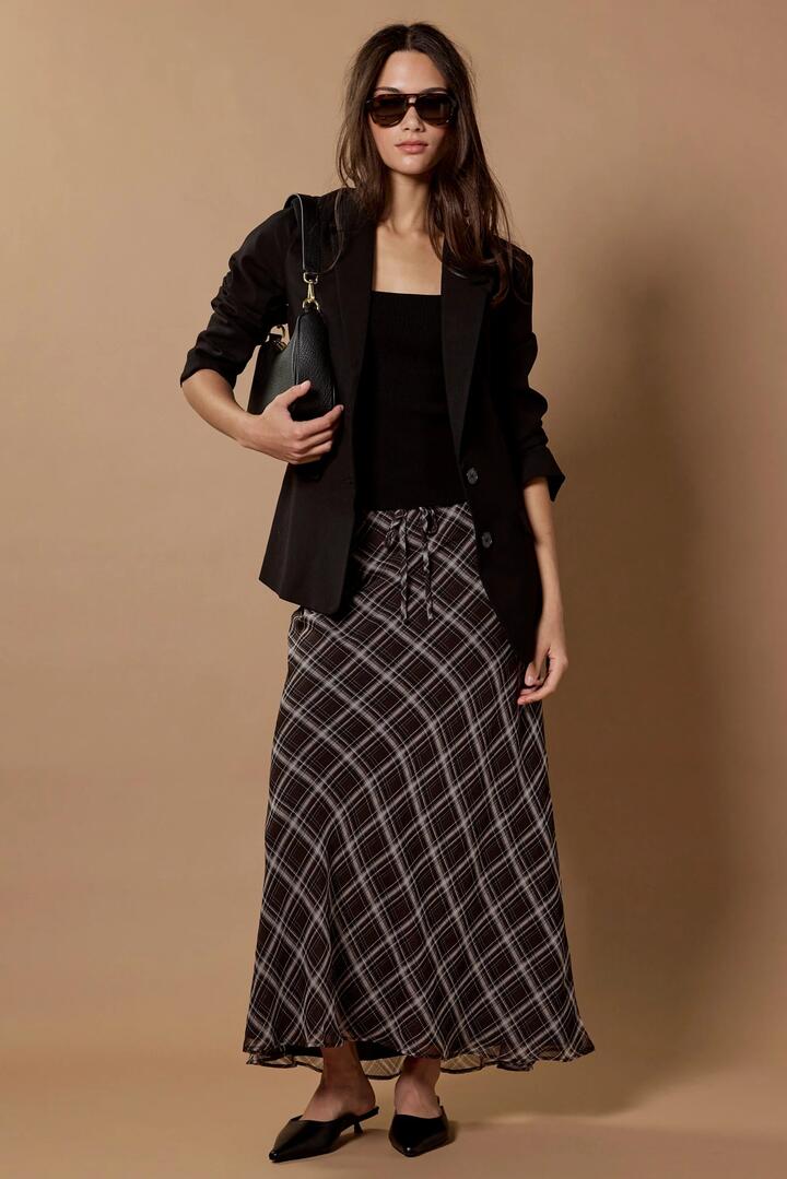 Image of a model wearing Skirts. Product name - Align Black Chocolate Check Tie Waist Bias Maxi Skirt in Black Chocolate Check colour by brand - Stories be Told