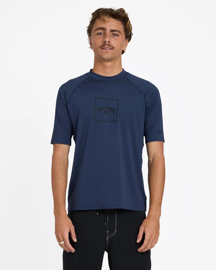 Image of a model wearing Tops. Product name - Billabong Mens Boxed Arch Short Sleeve Rash Vest Dusty Navy in Dusty Navy colour by brand - Billabong