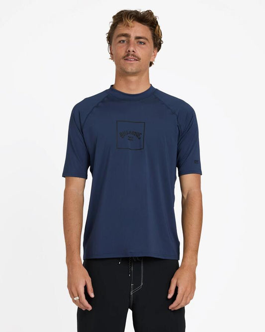 Image of a model wearing Tops. Product name - Billabong Mens Boxed Arch Short Sleeve Rash Vest Dusty Navy in Dusty Navy colour by brand - Billabong