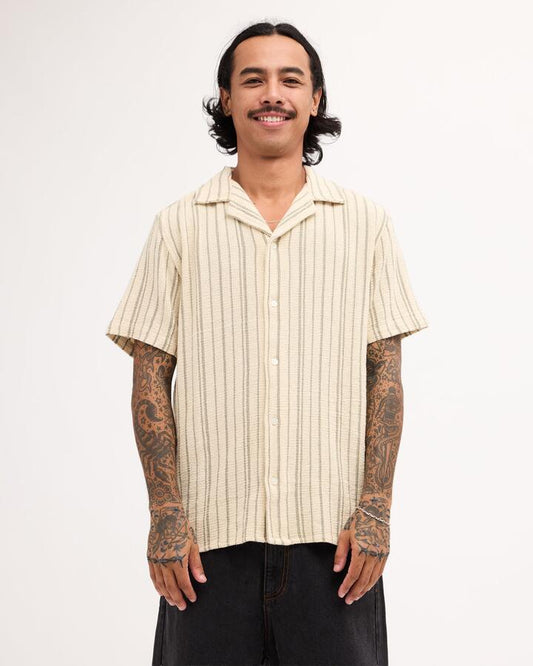 Image of a model wearing Tops. Product name - RVCA Mens Vacancy Stripe Short Sleeve Shirt Latte in Latte colour by brand - RVCA