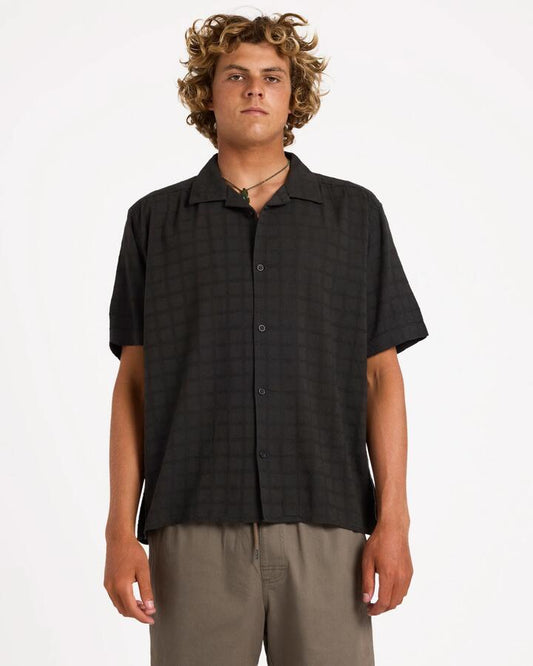 Image of a model wearing Tops. Product name - Rvca Mens Vacancy Short Sleeve Shirt Pirate Black in Pirate Black colour by brand - Rvca