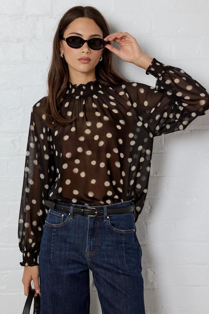 Image of a model wearing Tops. Product name - Emphatic Black Polka Dot Georgette High Neck LS Top in Black Polka Dot colour by brand - Ivy + Jack