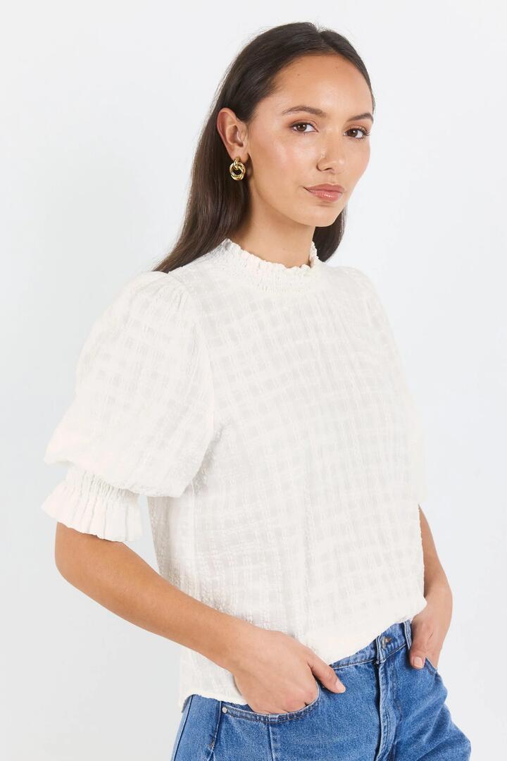 Image of a model wearing Tops. Product name - Affirming Ivory Self Check High Neck SS Top in Ivory Self Check colour by brand - Ivy + Jack
