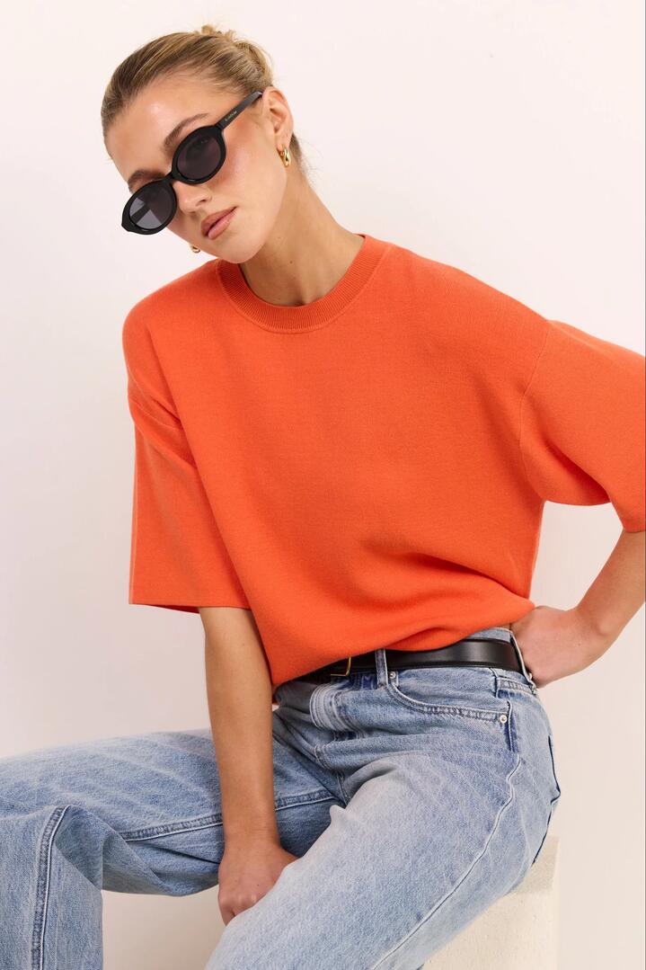 Image of a model wearing Outerwear. Product name - Intrepid Blood Orange Relaxed Knit Tee in Blood Orange colour by brand - Stories be Told