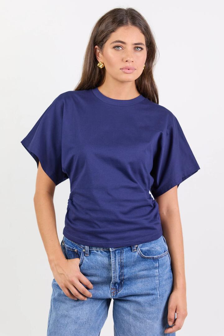 Image of a model wearing Tops. Product name - Cadence Ink Cotton Gathered Waist Detail Short Sleeve Tee in Ink colour by brand - RE:UNION Label