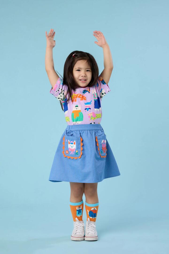 Image of a model wearing Skirts. Product name - Dogs Embroidery Kids Pocket Skirt in Denim colour by brand - Gorman